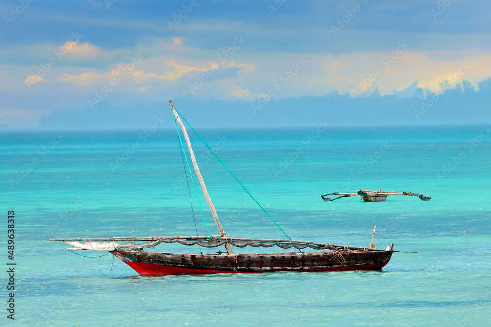A wooden sailboat (dhow) on the clear turquoise water of Zanzibar, Tanzania. A wooden sailboat (dhow) on the clear turquoise water of Zanzibar, Tanzania.