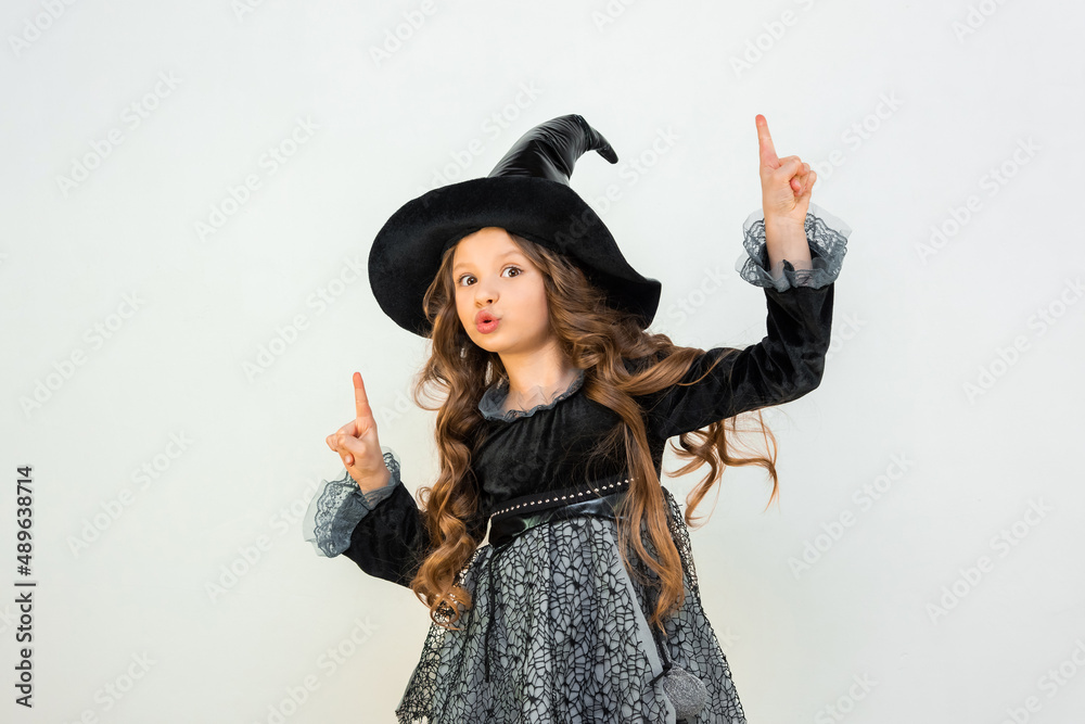 A cheerful witch on a white isolated background. A child at a Halloween party. A child in a magical costume. children's magic in action. A cheerful witch on a white isolated background. A child at a Halloween party. A child in a magical costume. children's magic in action.
