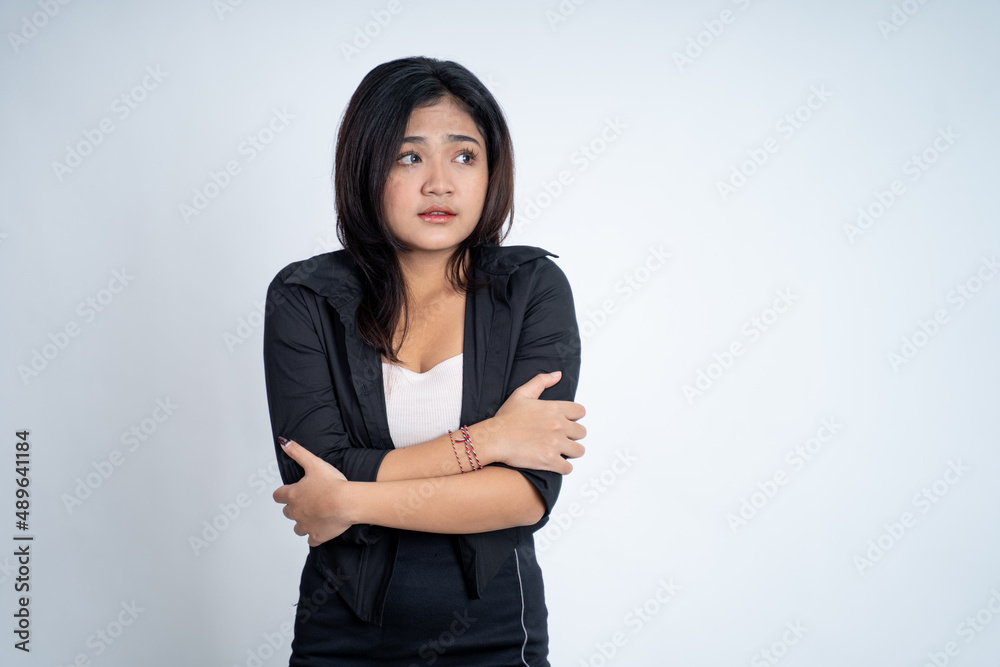 young woman feeling cold with both hands hugging her arms young woman feeling cold with both hands hugging her arms