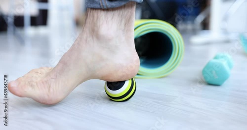 Man leg rolling sports ball for prevention and treatment of flat feet closeup photo