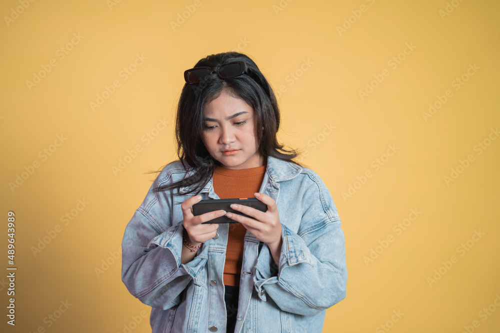 serious millennial asian girl playing game using mobile phone serious millennial asian girl playing game using mobile phone
