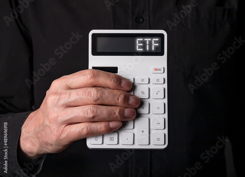 ETF investtments concept. Acronym on calculator in advisors hand.