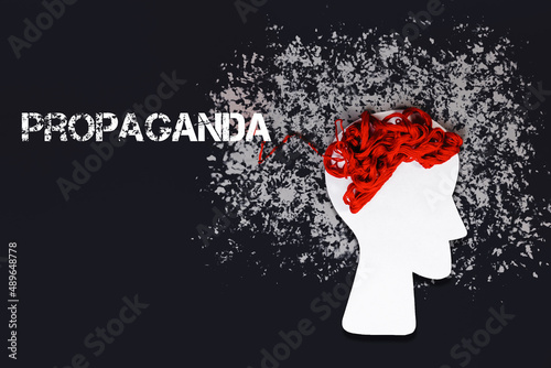 Paper silhouette of a head with red threads instead of brains on a black background. Flat lay. The concept of disinformation and propaganda photo