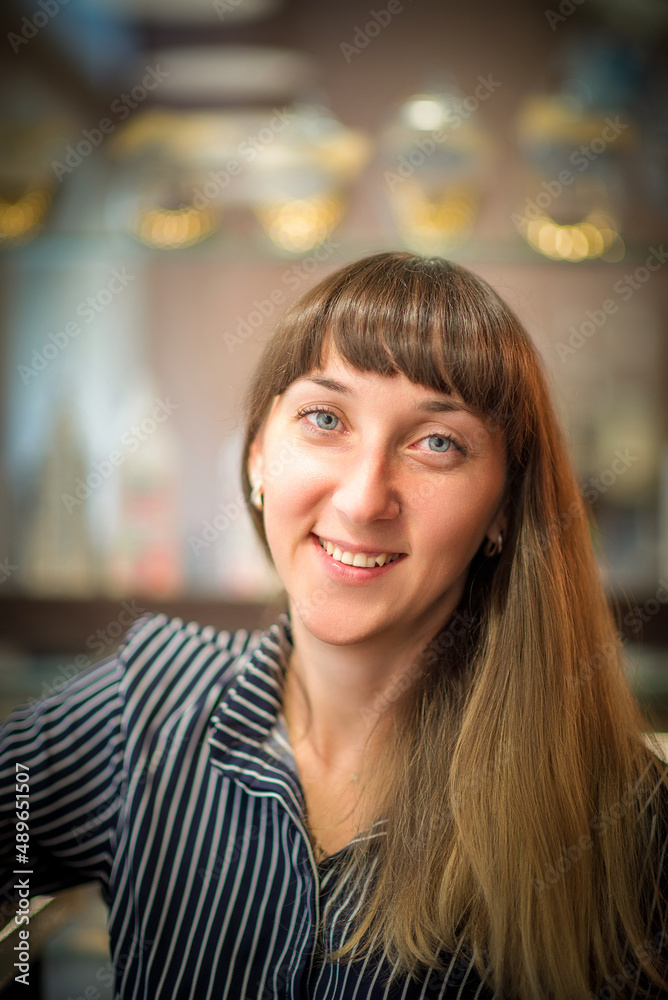 Portrait of a young beautiful blue-eyed girl in a cafe.
