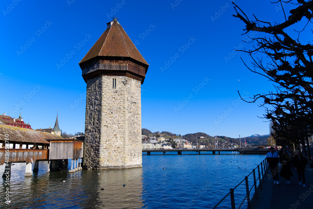 Medieval old town of Luzern with famous covered wooden Chapel Bridge (German: Kapellbrücke) and stone water tower on a sunny winter day. Photo taken February 9th, 2022, Lucerne, Switzerland.