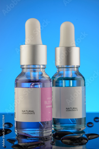 Bottle of liquid on a blue background with reflection. can be used as cosmetic oil