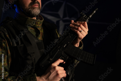 Close-up of soldier in military uniform with weapon on black background.