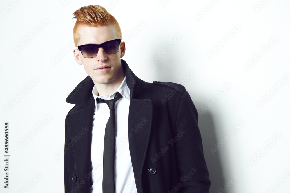 Feeling stylish. A red haired male looking at the camera in a suit and sunglasses with a white background.