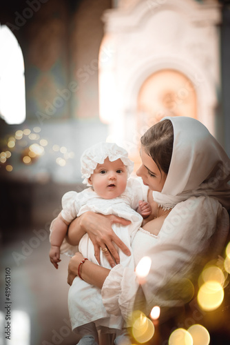 a mother with a small child in a temple or church prays near an icon and candles or came to a divine service in the Russian Orthodox church, the baptism of a baby