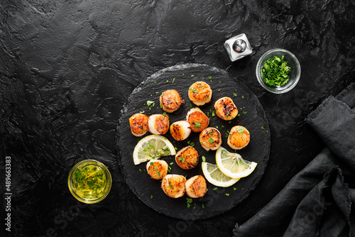 Grilled scallops with creamy lemon spicy sauce on black background. top view photo