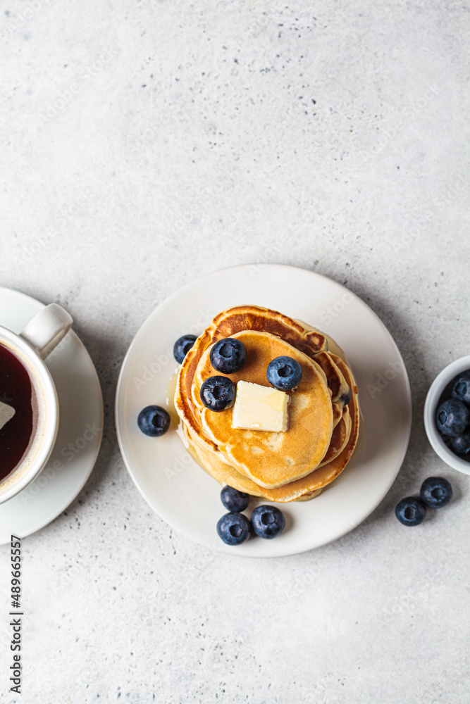 Stack of blueberry pancakes with maple syrup and butter on white plate for breakfast. Stack of blueberry pancakes with maple syrup and butter on white plate for breakfast.