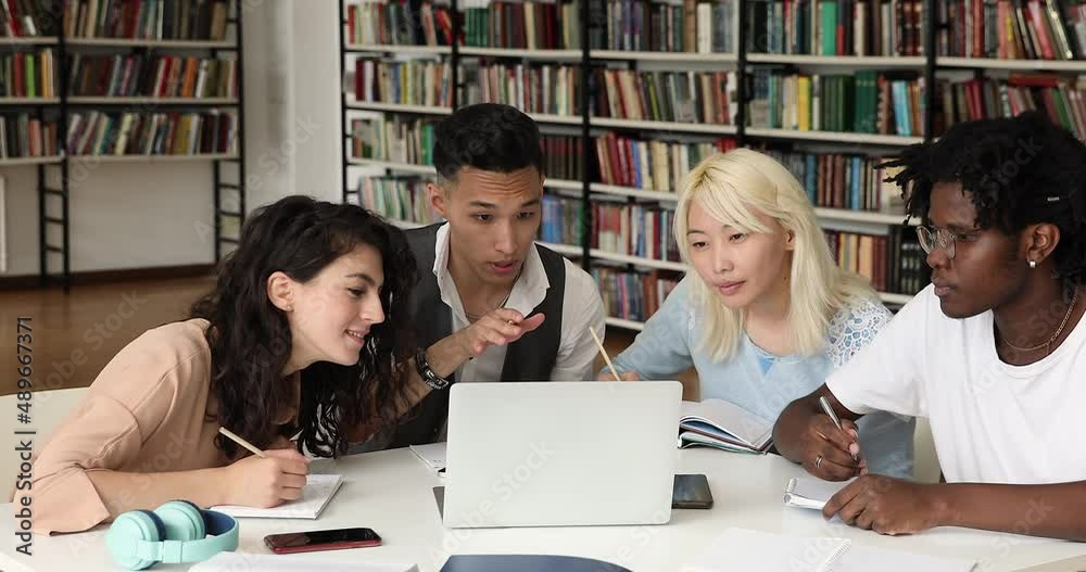 Four diverse teammates students study remotely using pc in scientific library discuss task make notes in workbooks. Motivated young people of some ethnic groups doing high school assignment together Four diverse teammates students study remotely using pc in scientific library discuss task make notes in workbooks. Motivated young people of some ethnic groups doing high school assignment together