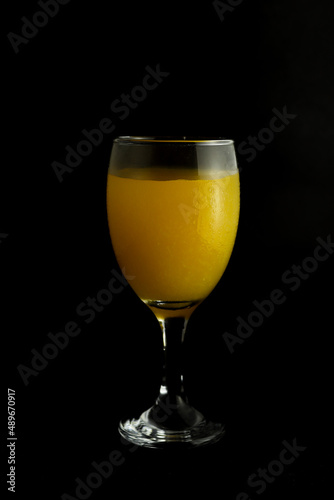 a glass of orange juice on black background