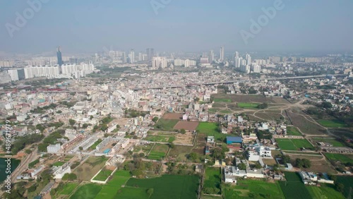 aerial panning shot showing densely populated houses, skyscrapers under construction, farms and feilds and a pond showing the scattered development of Indian cities like Gurgaon, Vijaywada, kolkata photo