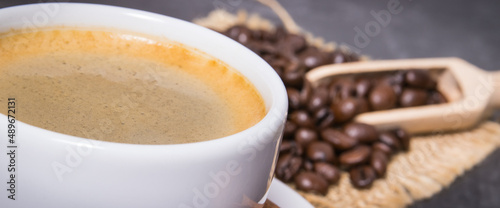 Coffee in white cup and roasted dark coffee beans with seasonings