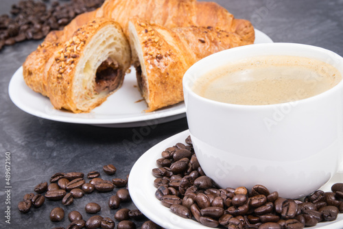 White cup of coffee and fresh croissant with chocolate