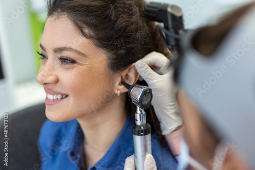 Close up of a female doctor carefully holding the ear of his patient to establish a clearer view of the inside of his ear, to see if he requires hearing aids at a modern clinic photo