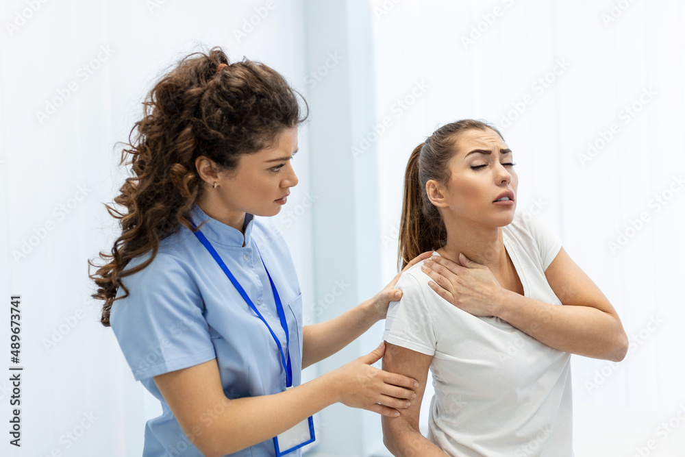 Woman doctor osteopath in medical uniform fixing woman patients shoulder and back joints in manual therapy clinic during visit. Professional osteopath during work with patient concept Woman doctor osteopath in medical uniform fixing woman patients shoulder and back joints in manual therapy clinic during visit. Professional osteopath during work with patient concept