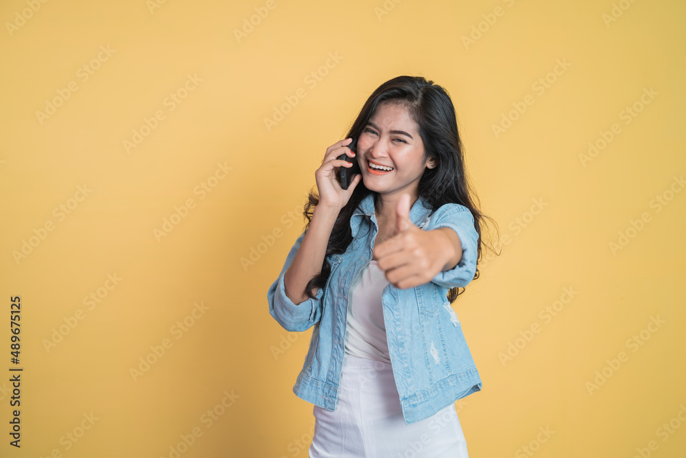 Young asian woman making a call using a mobile phone with thumbs up Young asian woman making a call using a mobile phone with thumbs up