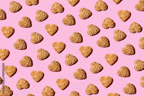 Heart shaped Oatmeal cookies, top view on trendy pink background. Creative Pattern made of cookies. Repeating Oatmeal cookies pattern. Flat lay style.