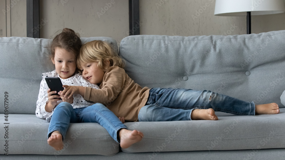 Full length happy bonding friendly little adorable kids siblings looking at  smartphone screen, enjoying spending time online playing video games or  watching funny cartoons without parental control. Stock Photo | Adobe Stock