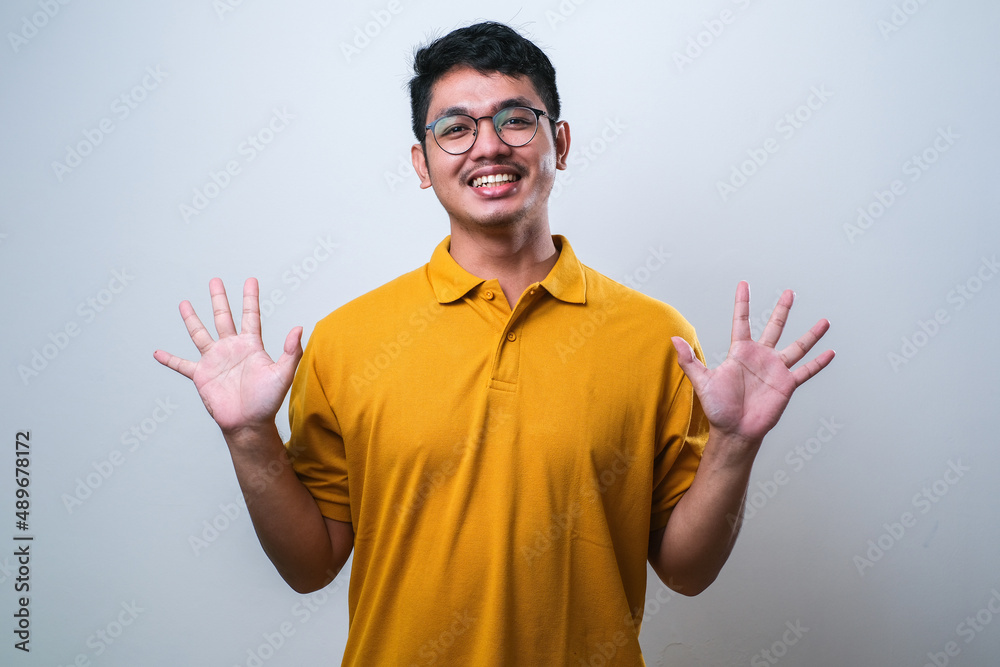Asian young man showing and pointing up with fingers number ten