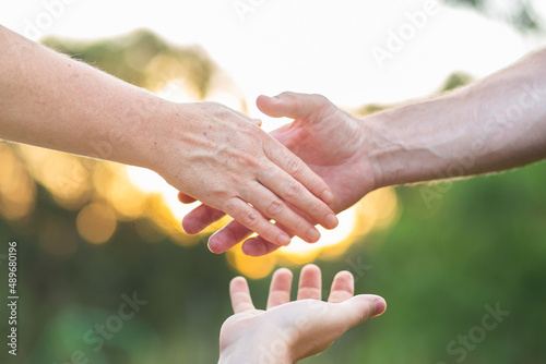 Middle aged hands of a man and woman about to shake with mediators hand helping them to agree photo