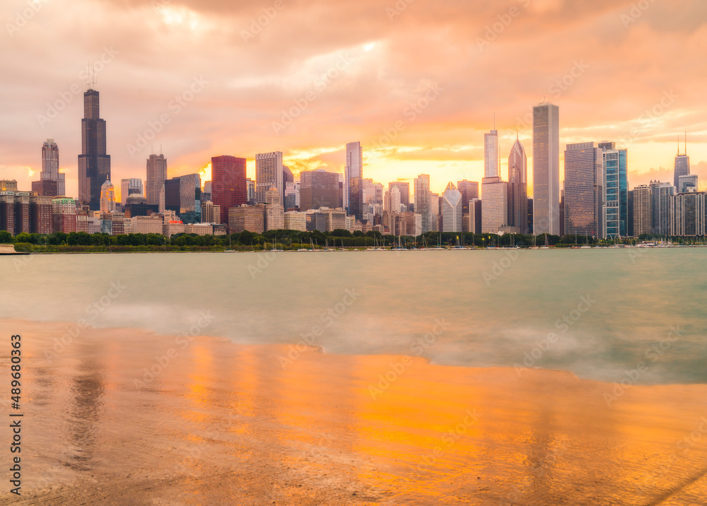 Naklejka premium chicago,illinois,usa. 8-11-17: Chicago skyline at sunset with cloudy sky and reflection in water.