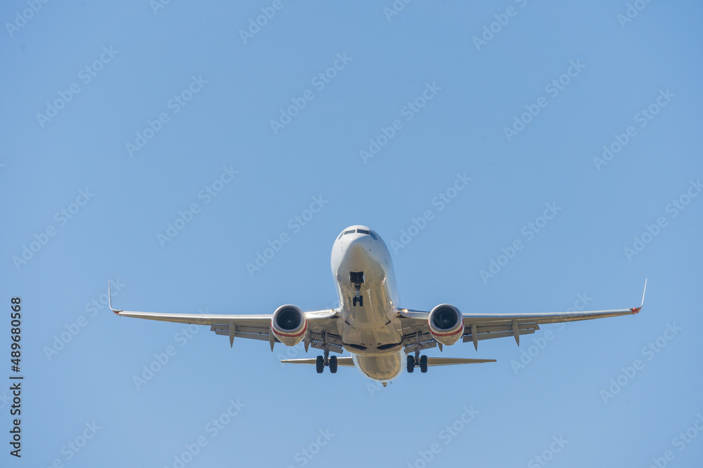 Looking up at a large jet aeroplane against a blue sky Looking up at a large jet aeroplane against a blue sky