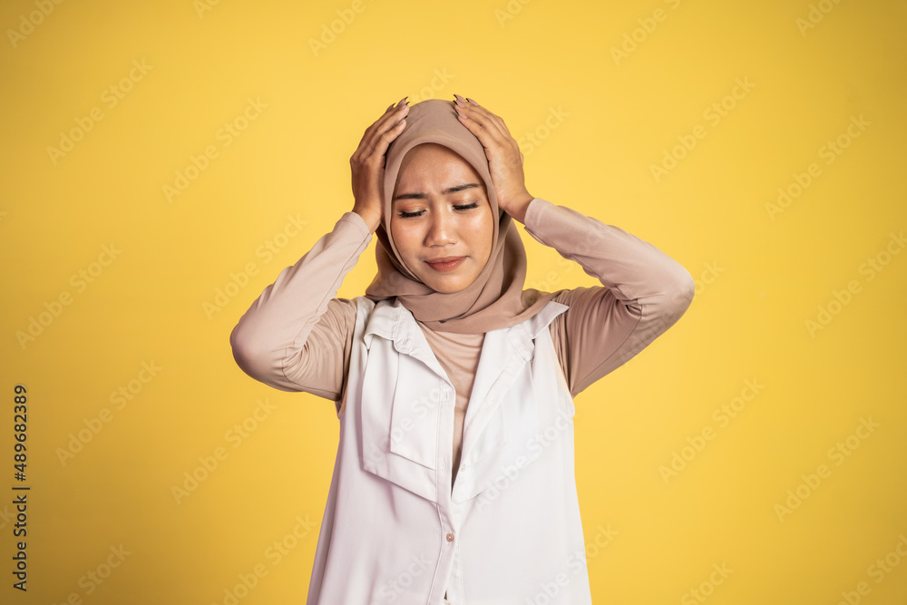 Asian woman in hijab holding head with headache Asian woman in hijab holding head with headache