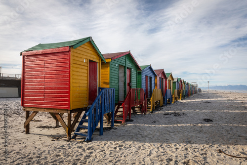 Reihe von bunten Strandhäusern am weißen Sandstrand von Muizenberg (Südafrika) in strahlendem Gelb, Rot, Blau und Grün photo