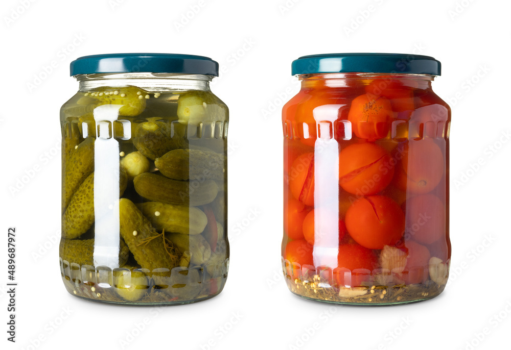 The two glass jar with cucumbers and tomatoes on a white background The two glass jar with cucumbers and tomatoes on a white background
