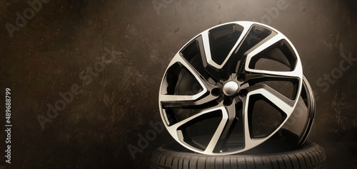 new stylish cool alloy wheel on the tire dark textured background  beautiful and expensive 20 -21  22  large diameter copy space on the left
