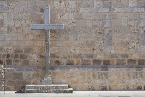 large stone cross in front of a church wall