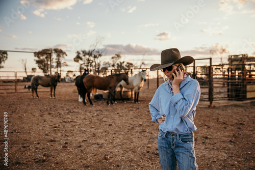 teenager standing near horses talking on her mobile photo