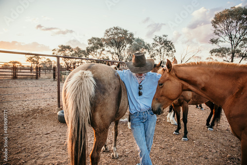 Teenage girl standing between horses looking down photo