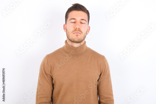 young caucasian man wearing grey turtleneck over white background looking sleepy and tired, exhausted for fatigue and hangover, lazy eyes in the morning. © Roquillo