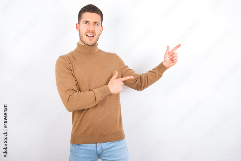 young caucasian man wearing grey turtleneck over white background point at copyspace recommend sales discounts young caucasian man wearing grey turtleneck over white background point at copyspace recommend sales discounts