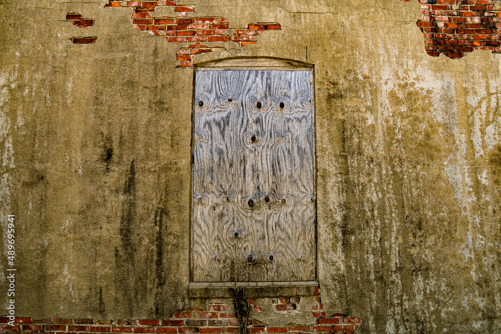 Naklejka premium damaged rural abandoned stucco brick alley wall boarded up window building door closed empty dirty warehouse structure