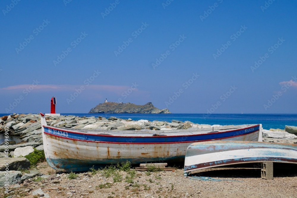 Old wooden fishing boats in Bercaggio, charming seaside village in Cap Corse, Corsica, France. Ile de la Giraglia in the background.