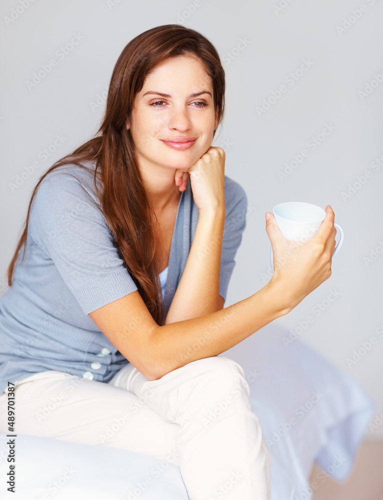 Thoughtful female drinking a cup of coffee at the bedroom. Day dreaming - Pretty casual female drinking coffee and sitting relaxed on the bed. Thoughtful female drinking a cup of coffee at the bedroom. Day dreaming - Pretty casual female drinking coffee and sitting relaxed on the bed.