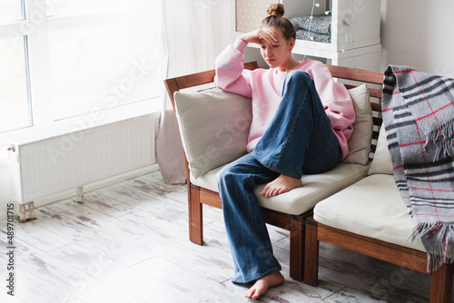 Tableau sur toile Sad young woman depressed sitting at home on the couch Abuse or domestic violenc