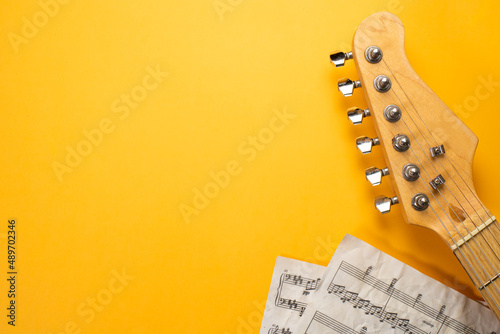 Closeup of electric guitar neck with musical score in solid yellow background, Banner, Overhead with copy space