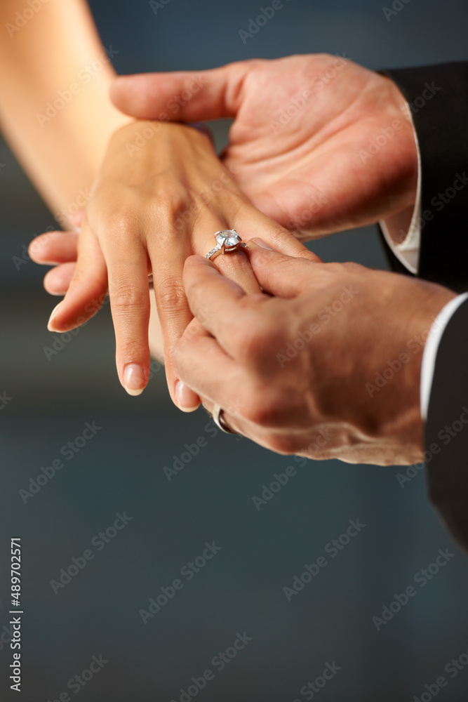 Making a vow. Cropped view of a groom slipping a ring on to his brides finger. Making a vow. Cropped view of a groom slipping a ring on to his brides finger.