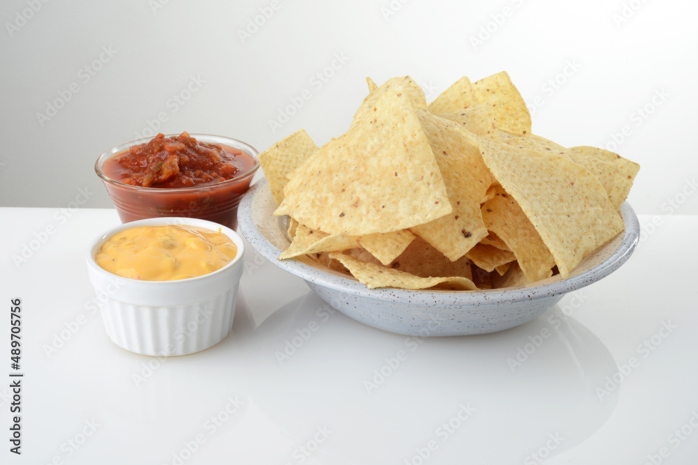 bowl of nacho chips with salsa and cheese on white table top bowl of nacho chips with salsa and cheese on white table top