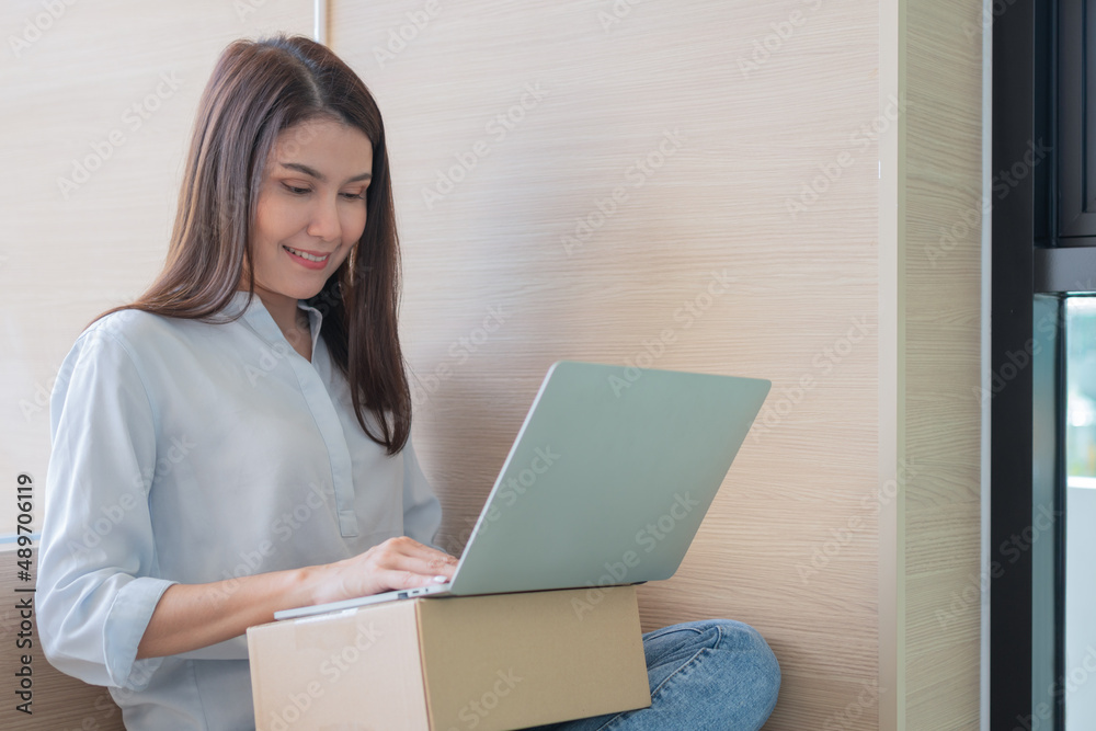 Happy young Asian woman entrepreneur, Smile for sales success after checking order from online shopping store in a laptop at home office, Concept of merchant business online and eCommerce