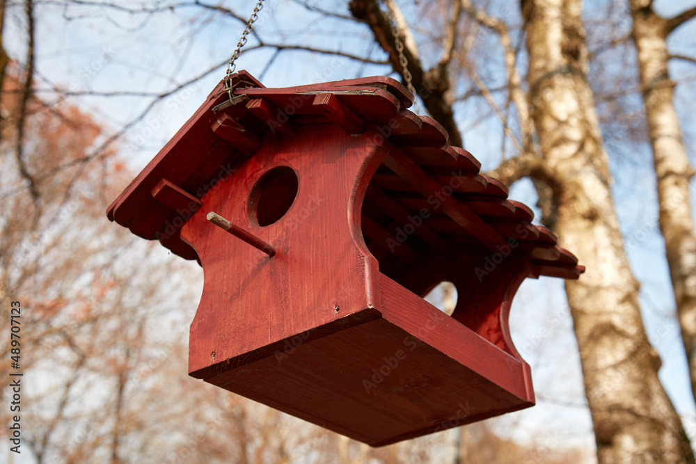Red wooden birdhouse hanging on a tree branch. Red wooden birdhouse hanging on a tree branch.