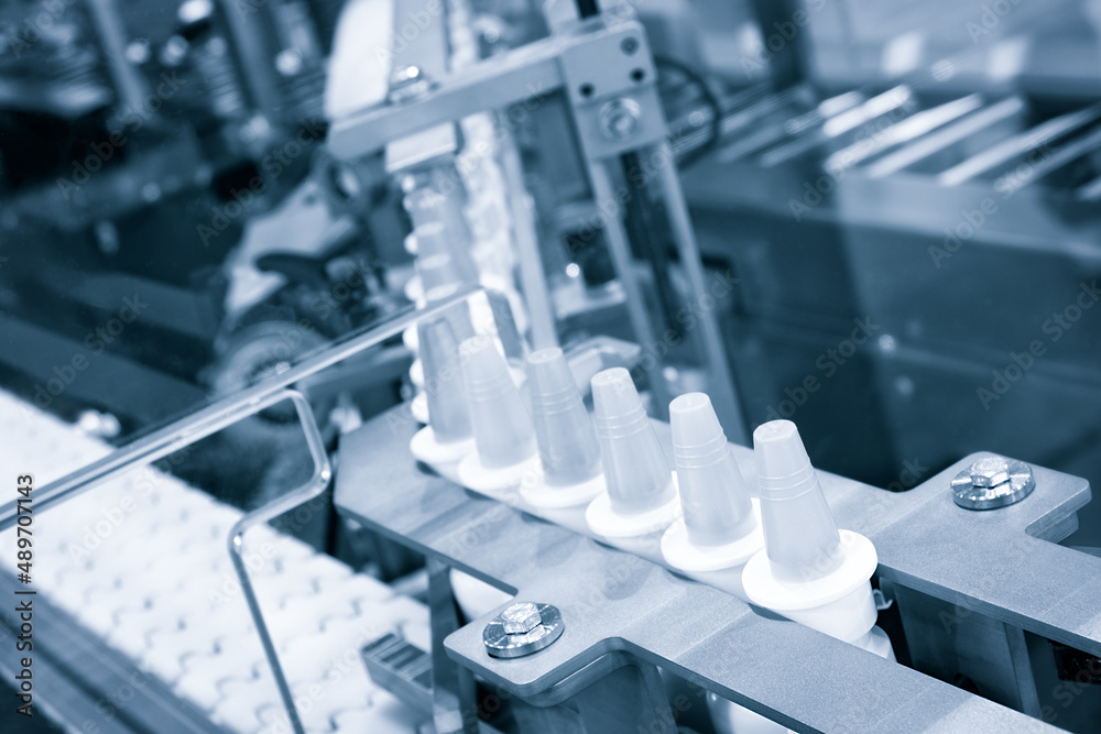 Close-up Many white plastic spray bottles for packaging liquid medicines or cosmetics in a row on a conveyor belt in a pharmaceutical manufacturing factory