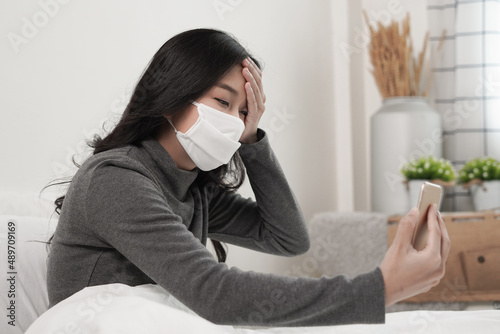 Young woman sick using smartphone to chat and talk with doctor via video conference Medical App or online video call to consult her symptoms during quarantine at home