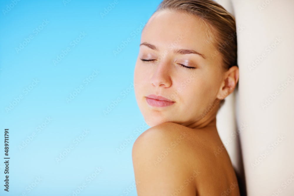 Young female woman leaning against the wall with eyes closed. Elegant topless woman leaning against the wall with the blue sky as the background. Young female woman leaning against the wall with eyes closed. Elegant topless woman leaning against the wall with the blue sky as the background.